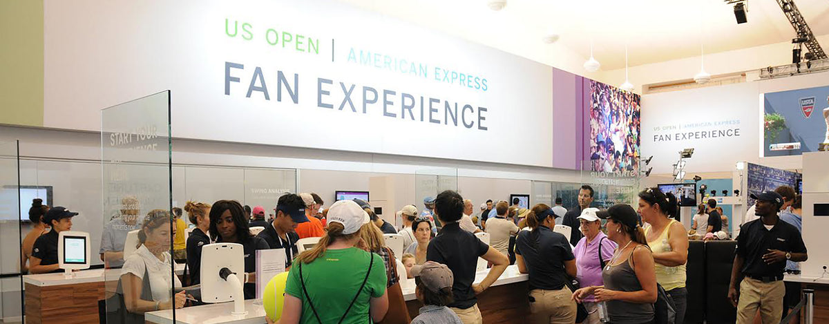 US Open American Express Fan Experience branded display wall with tablet kiosks and a crowd of attendees
